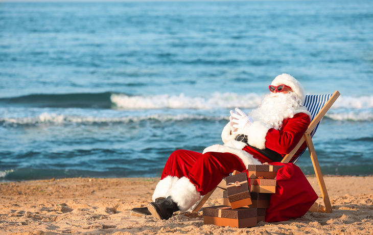 Weihnachtsmann mit Geschenken am Strand