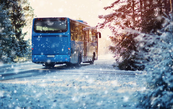 Bus auf Winterstraße durch Nadelwald