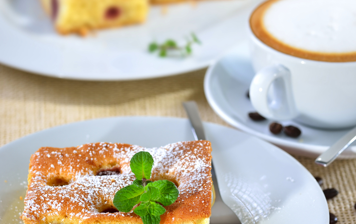 Frisch gebackener Kirschkuchen mit einer Tasse Cappuccino