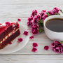 Roter Samtkuchen,Tasse Kaffee und rosa Nelken auf Holztisch